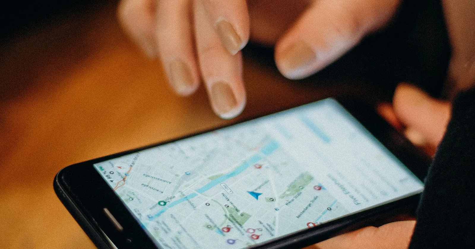 Ruka drži telefon s otvorenom Google kartom i oznakama lokacija