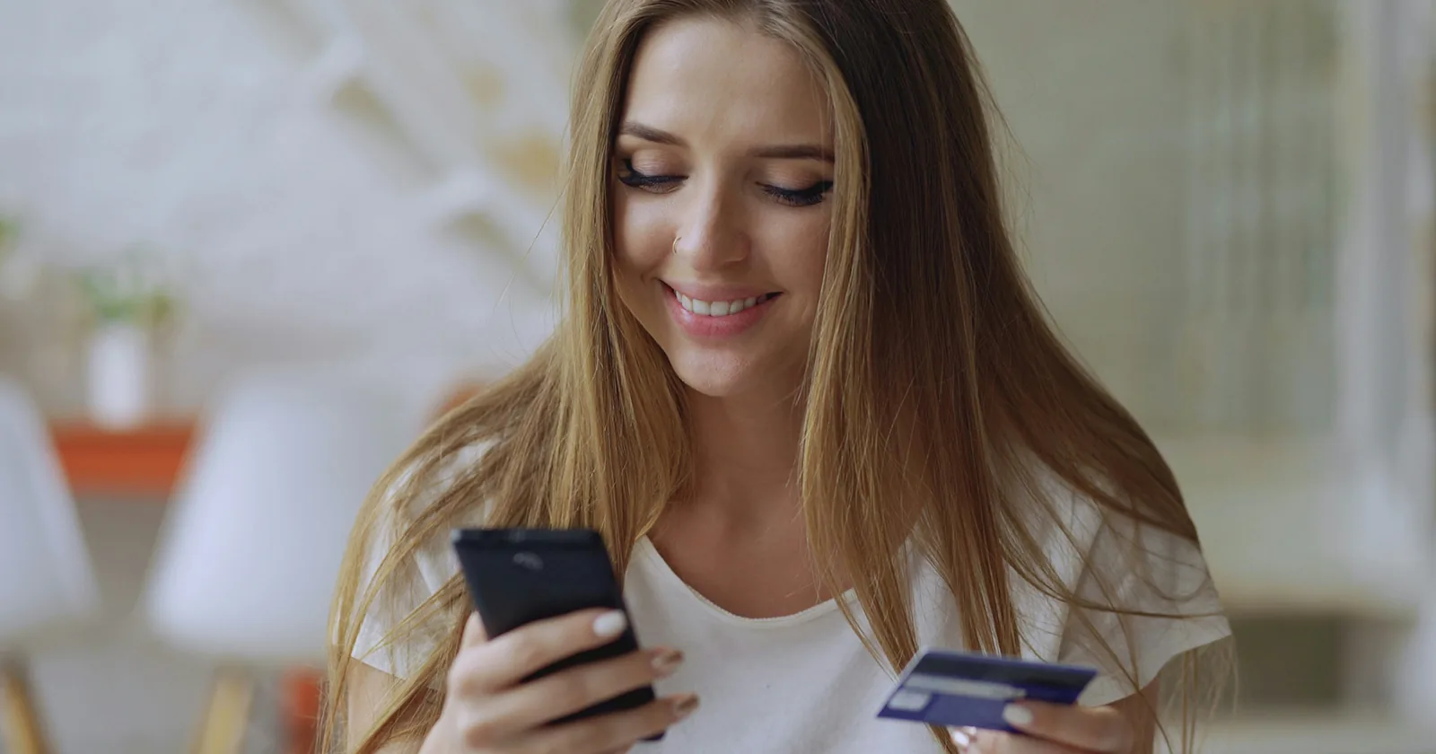 Žena kupuje putem mobitela s bankovnom karticom u ruci